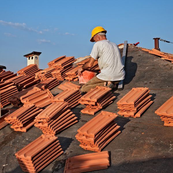 A roofer installs terracotta tiles during a major re-roofing project, completed by Roofing Guys Perth.