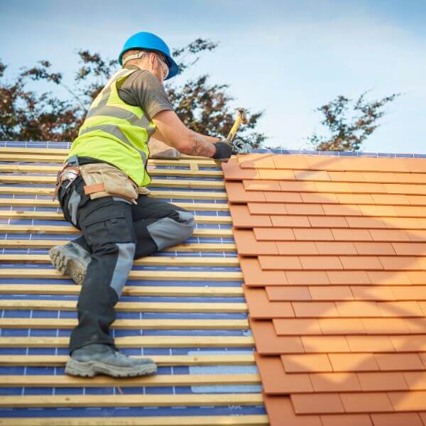 A skilled roofer installs terracotta tiles on a pitched roof, part of a full re-roof completed by Roofing Guys Perth. A skilled roofer installs terracotta tiles on a pitched roof, part of a full re-roof completed by Roofing Guys Perth.