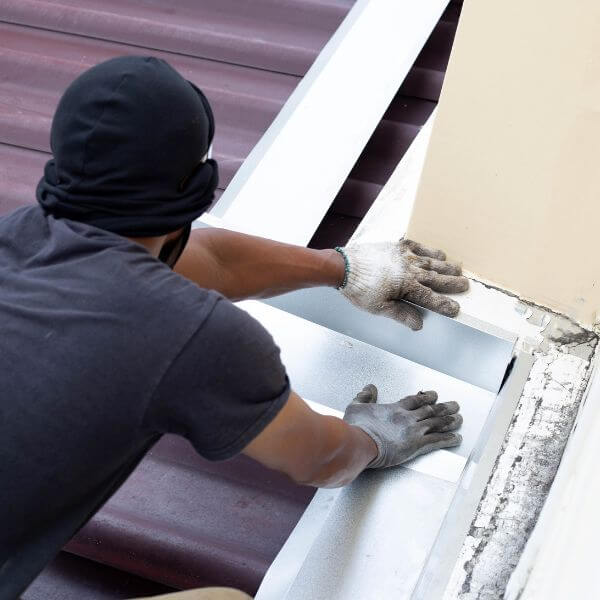 Roofing technician sealing roof joins and fixing flashing, part of expert repair work by Roofing Guys Perth to prevent leaks and rust damage.