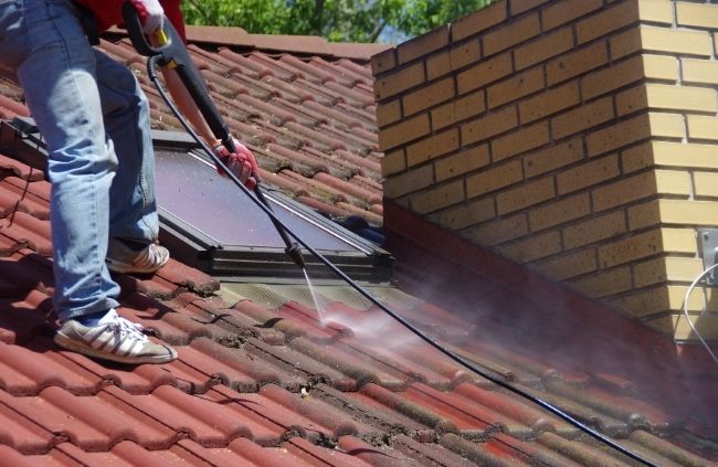 Roofer carrying out roof cleaning with Roofing Guys Perth, using high-pressure washing to remove buildup and debris.