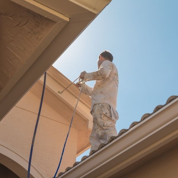 Roofer performing roof painting in Perth, sealing and refreshing tiles to withstand local heat and heavy rain.