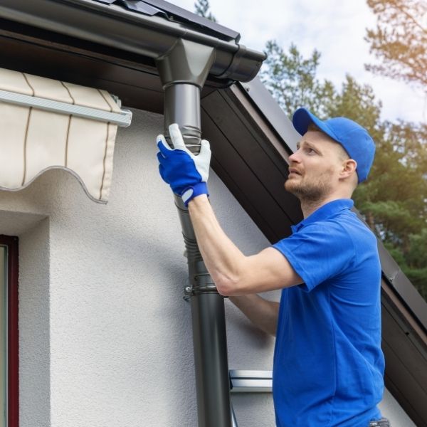 Technician from Roofing Guys Perth repairing gutters and securing new downpipe fittings to stop overflow issues.